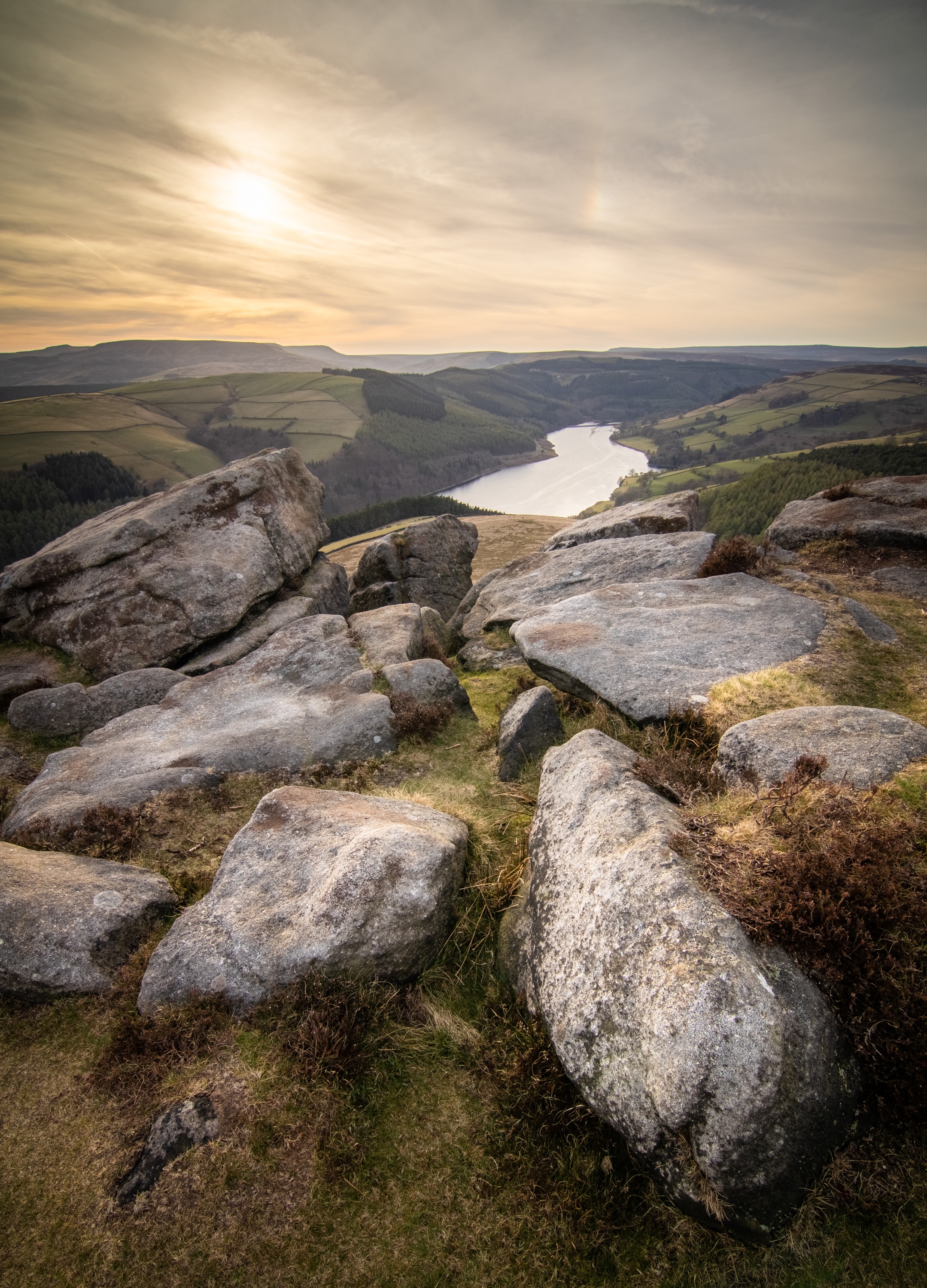 The sun setting through hazy cloud over Ladybower Reservoir in the UK's Peak District National Park, taken from Whinstone Lee Tor at the south end of Derwent Edge.
